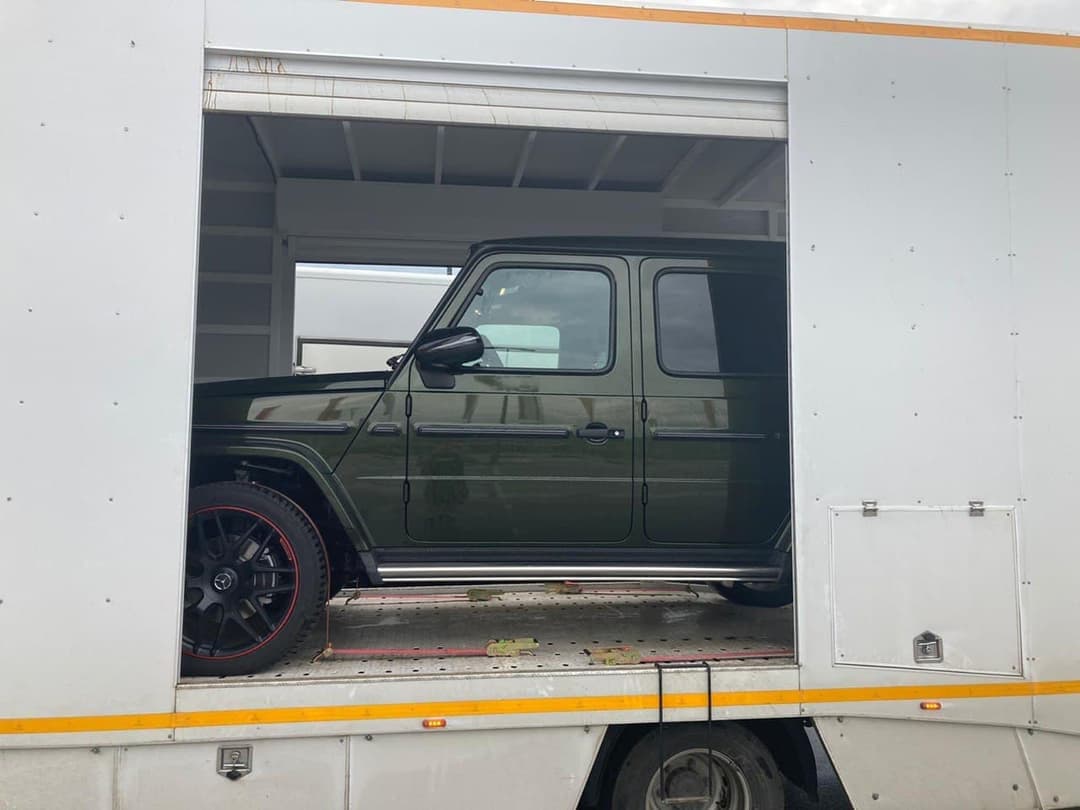 Mercedes-AMG G 63 оливкового цвета в одноместном закрытом автовозе с полностью открытым боковым бортом, закреплён ремнями на перфорированном полу